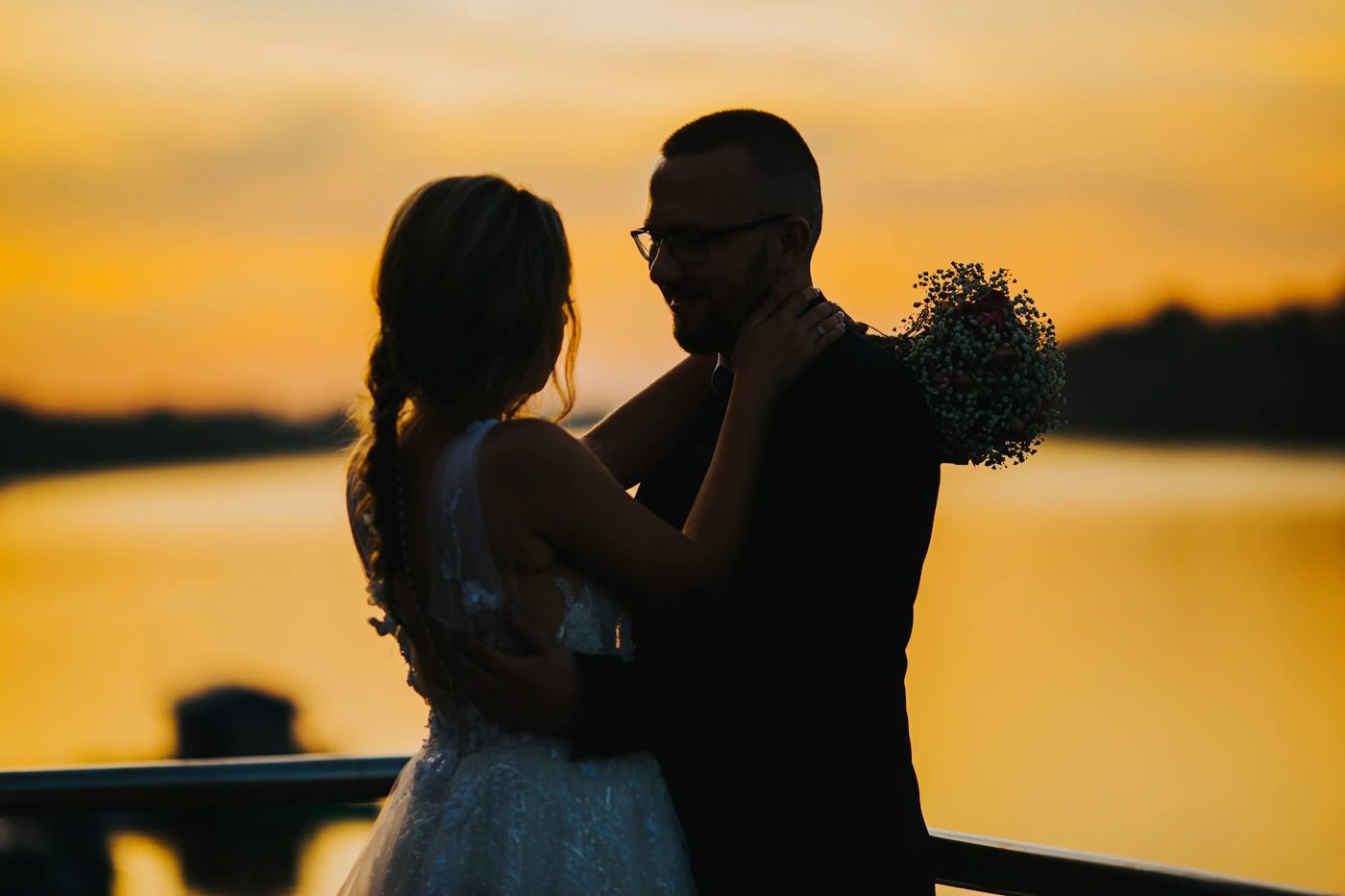 Romantic silhouette of bride and groom embracing against a brilliant golden sunset sky during elopement portrait session outdoors