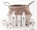 A woven basket with handles holds three cylindrical skincare product bottles labeled ONNE, which include a pump bottle, a spray bottle, and a smaller cream bottle. Around the basket are two decorative spherical ornaments made of glass and twine, and some smooth stones.