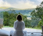 sitting woman in white robe looking at mountains during daytime