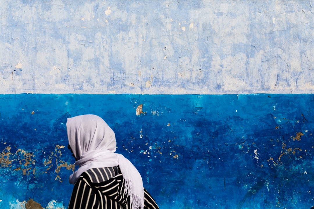 woman wearing white hijab beside blue and gray painted wall