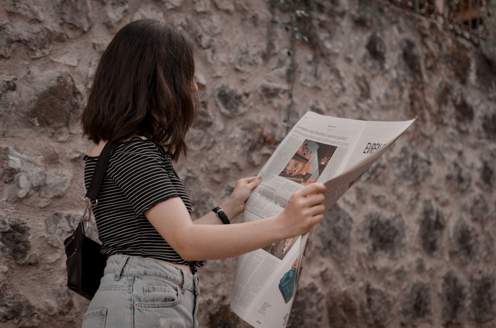 women's white striped t-shirt reading a newspaper