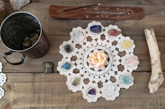 An overhead view of a voodoo doll surrounded by candles and herbs on a wooden table.