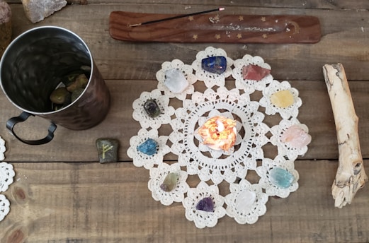 An overhead view of a voodoo doll surrounded by candles and herbs on a wooden table.