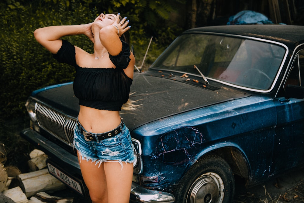 femme portant un crop top noir avec la tête haute debout devant un véhicule noir