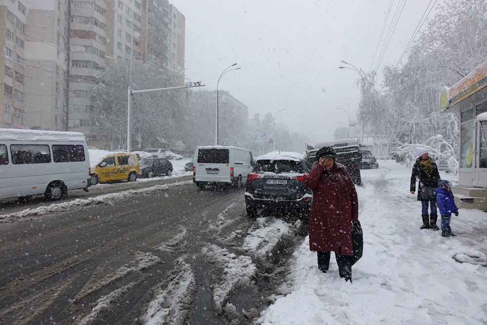 three people standing beside road covered with snow during daytime