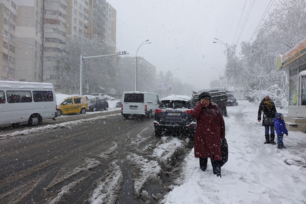 drei Personen, die tagsüber neben einer schneebedeckten Straße stehen