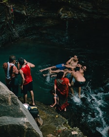 Families enjoying a sparkling natural pool with forested hills in the background.