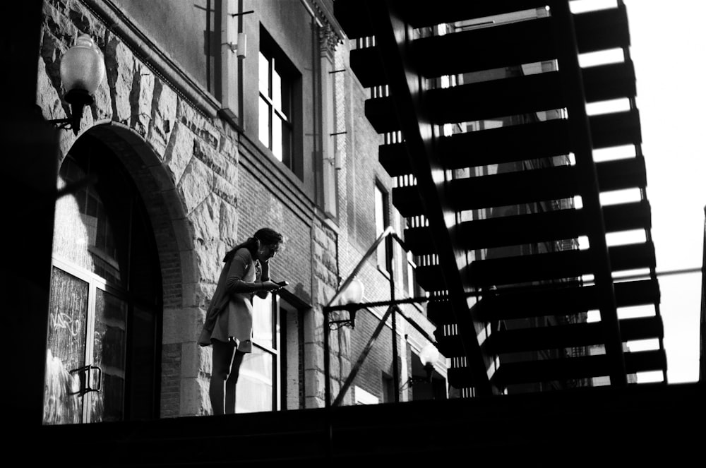 greyscale photo of person standing near railings