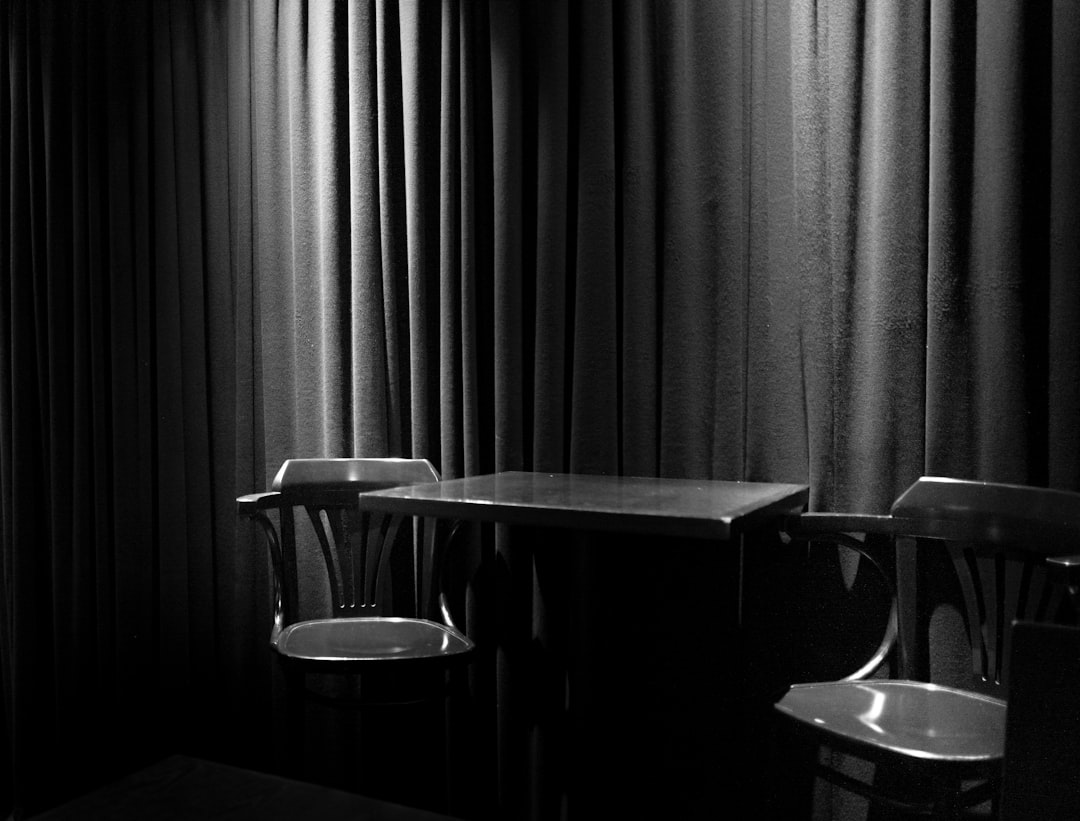 greyscale photograph of chairs beside table inside room