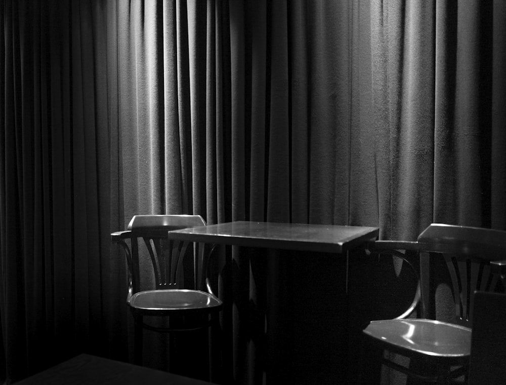 greyscale photograph of chairs beside table inside room