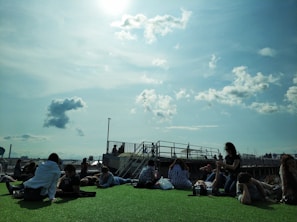 A serene rooftop scene featuring a small group enjoying the open air with soft cushions and plants.