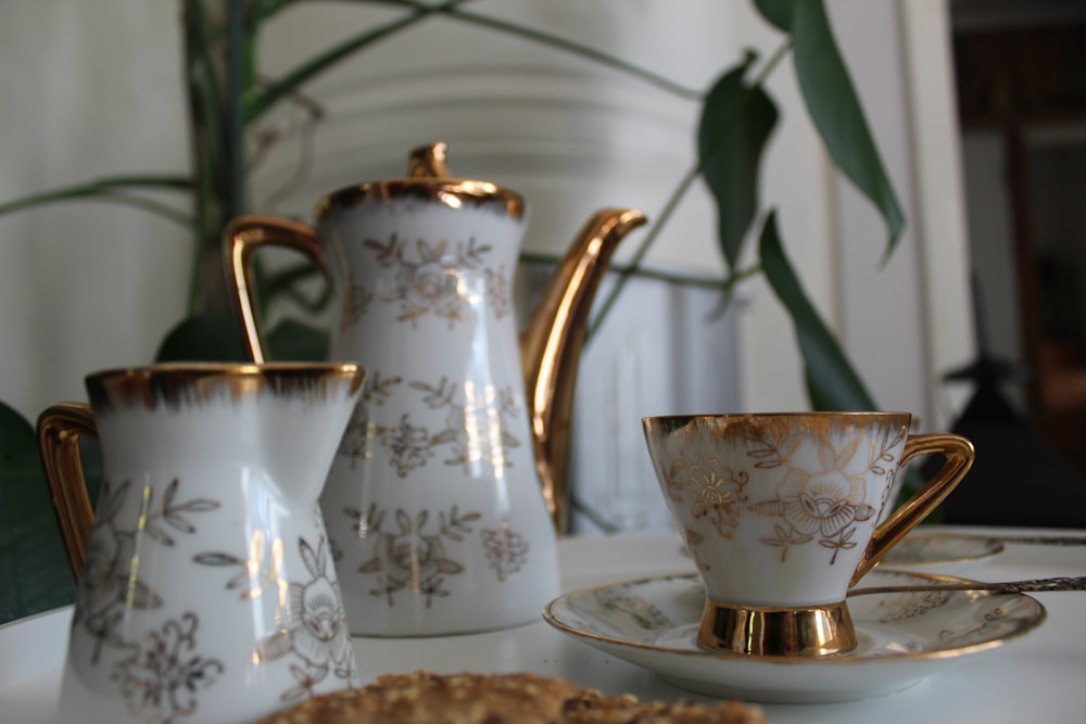 white and gold pitcher with cup and saucer