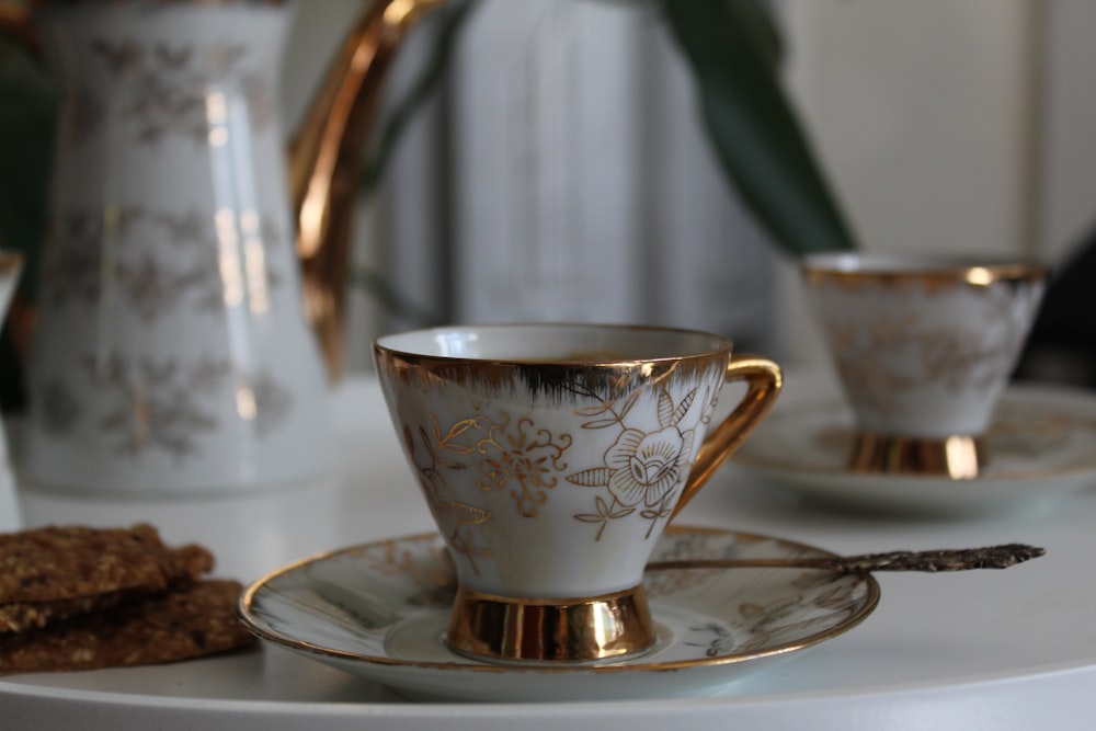 white and gold floral ceramic cup and saucer