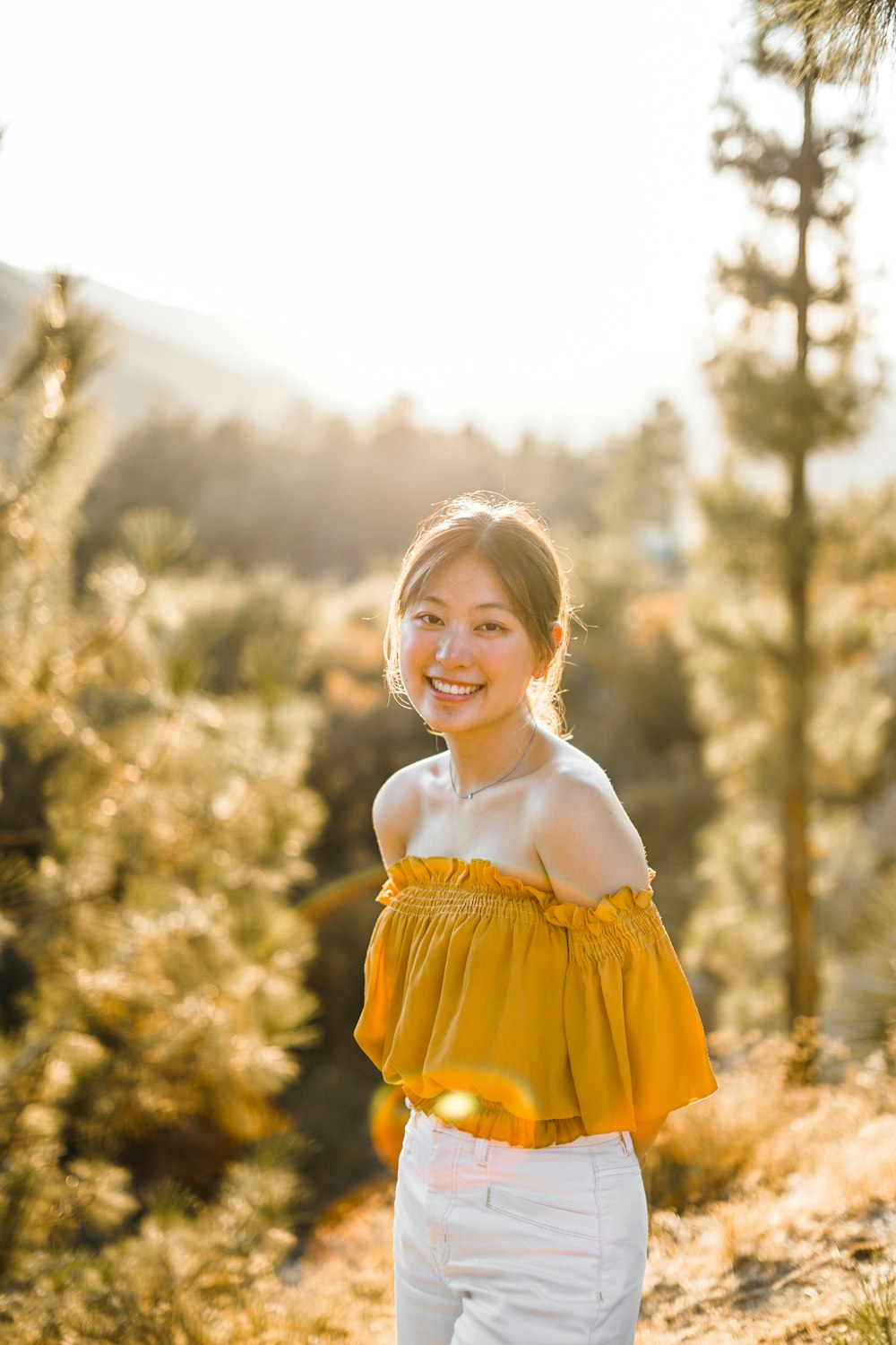 Mujer con top amarillo con hombros descubiertos y pantalones blancos