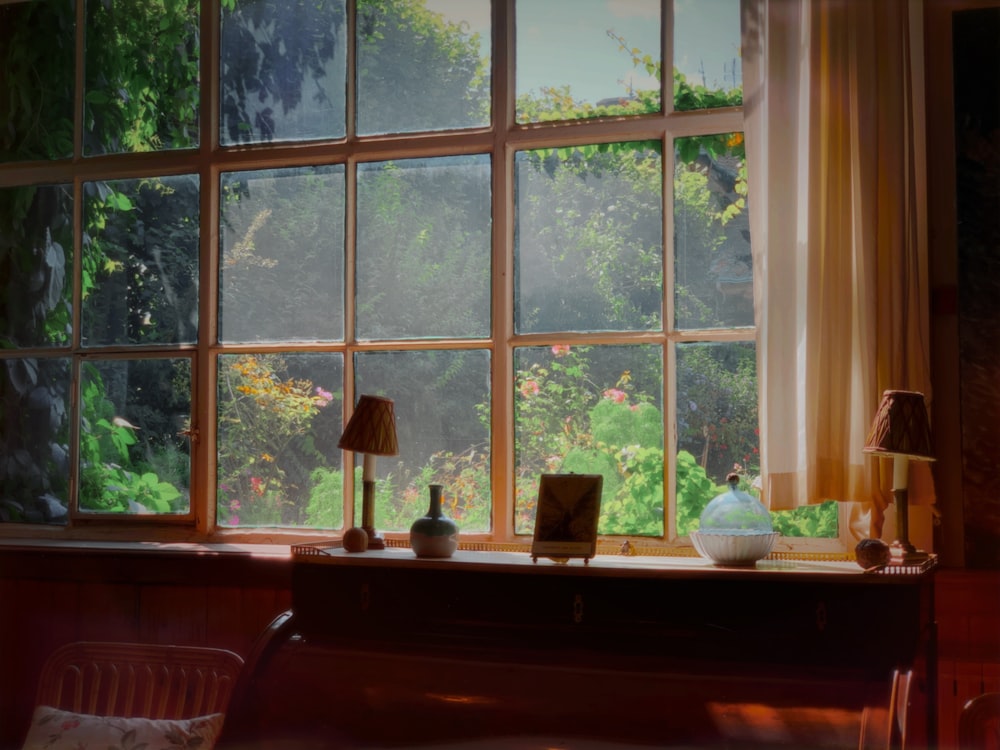 scrivania in legno marrone con lampade da tavolo accanto alla finestra