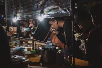 Happy customers enjoying food from a mobile food stall in a lively neighborhood setting.