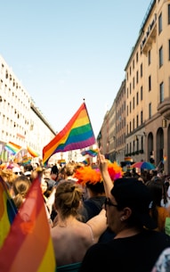a crowd of people holding rainbow colored flags