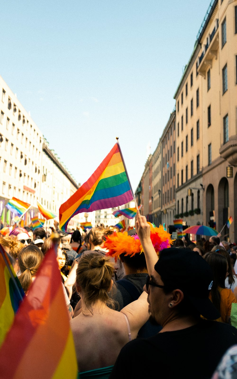 a crowd of people holding rainbow colored flags