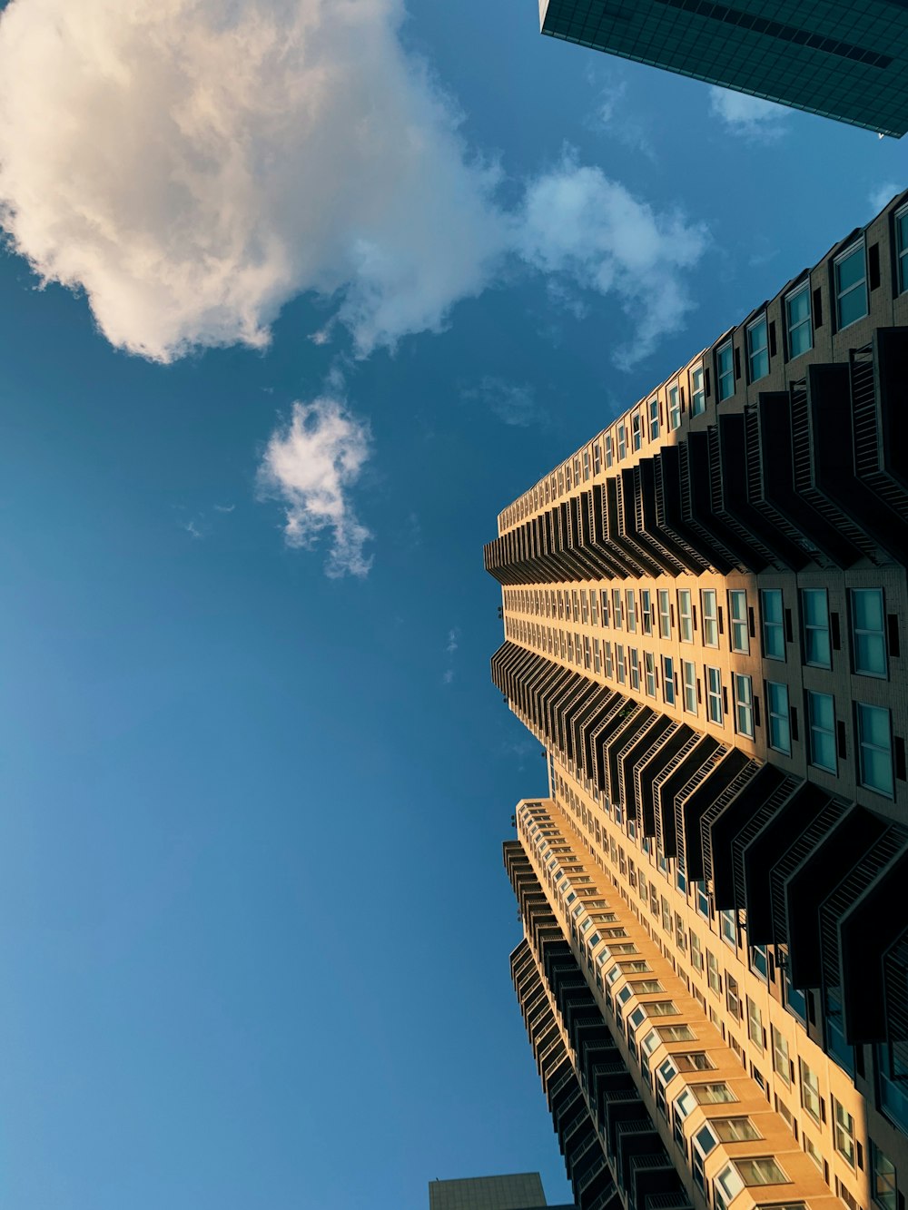 looking up at a tall building with a cloud in the sky