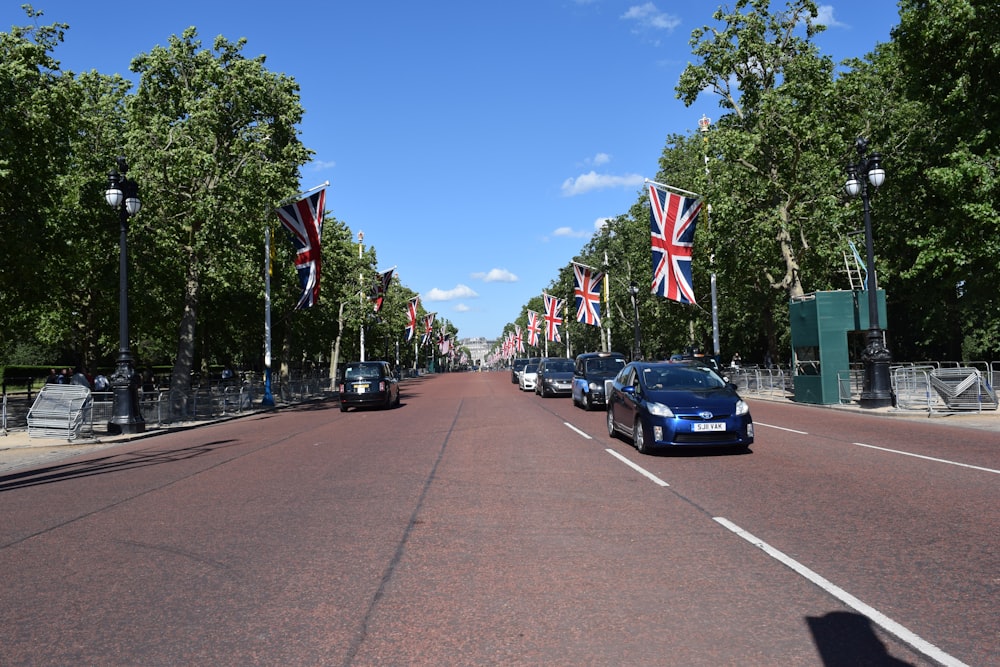 vehicles in road surrounded by trees and flags during daytime