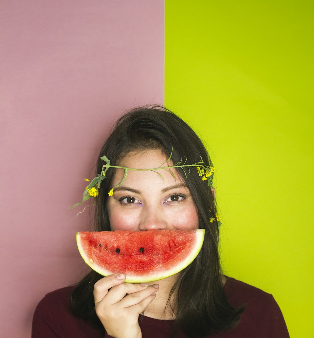 woman wearing maroon shirt holding sliced watermelon