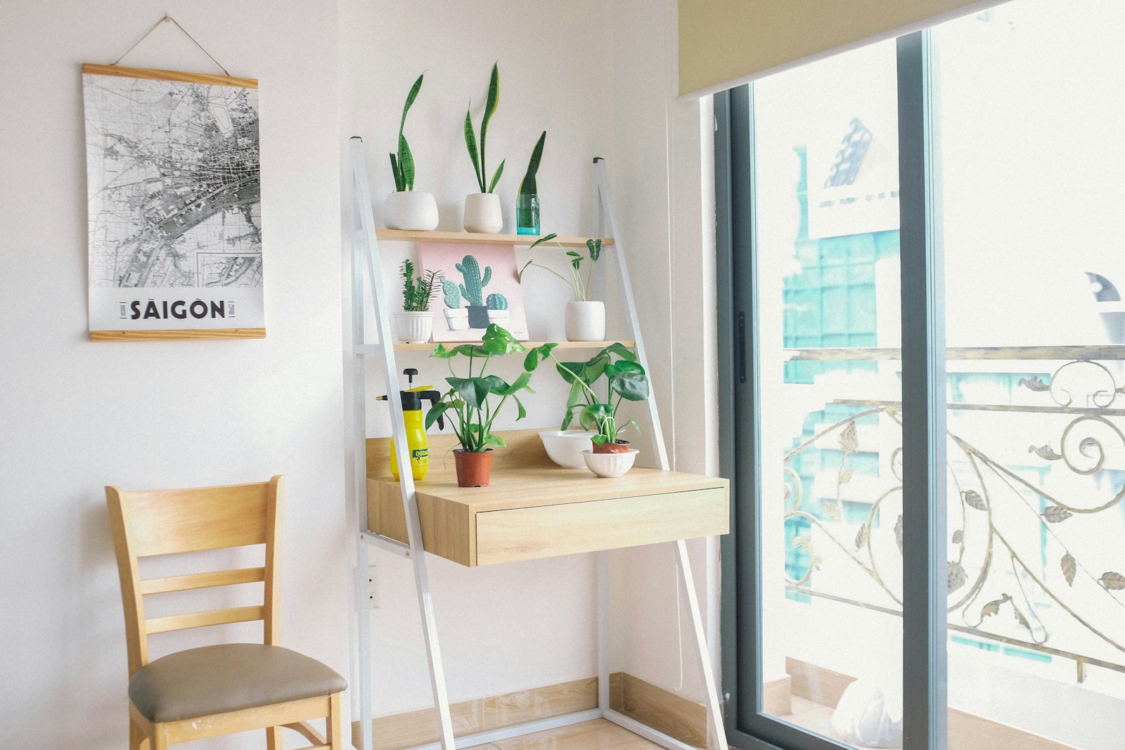 small apartment desk corner with ladder shelf snake plants and city map art