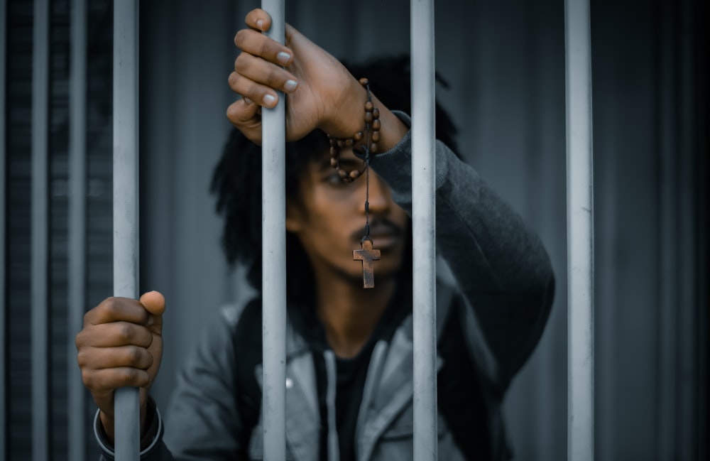 man behind bars wearing cross bracelet