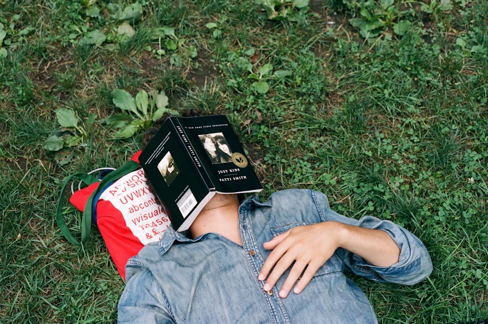 person lying on grass with book face
