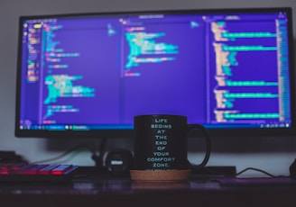 flat screen monitor and black ceramic mug