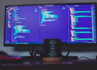 flat screen monitor and black ceramic mug