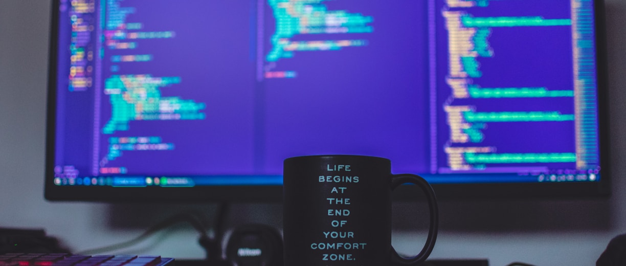 flat screen monitor and black ceramic mug