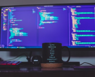 flat screen monitor and black ceramic mug