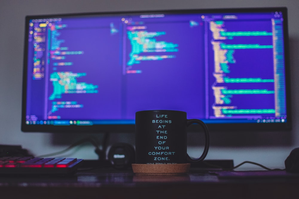 flat screen monitor and black ceramic mug