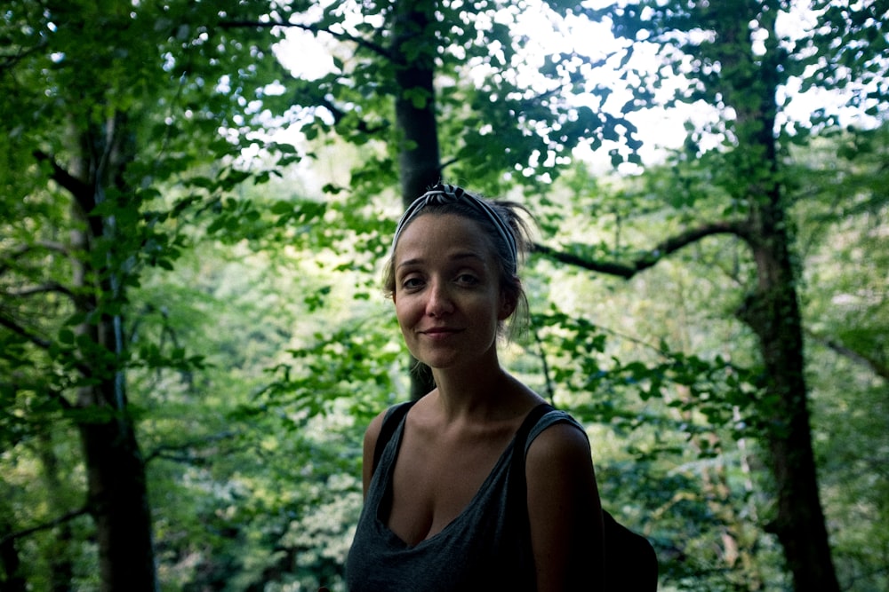 woman wearing gray tank top across green trees