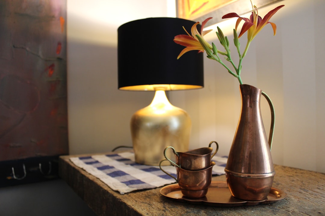 gold and black table lamp on table beside wall