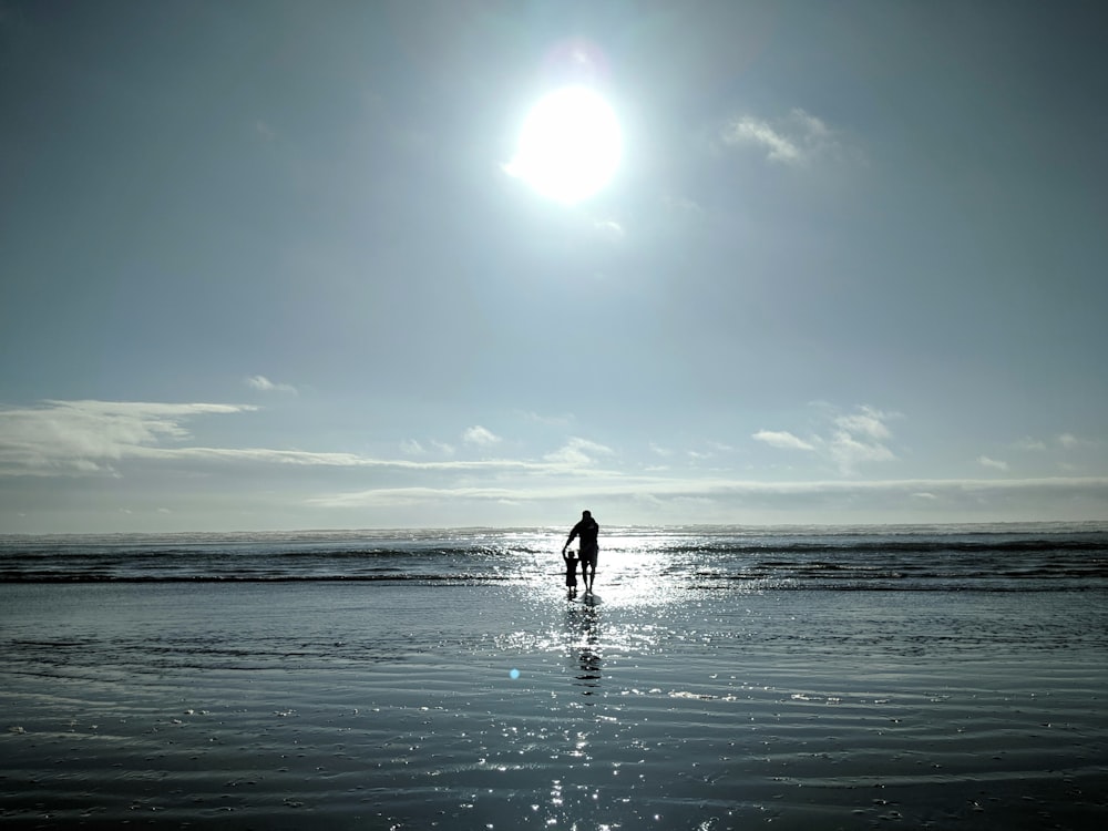 Mann und Kleinkind gehen am Meeresufer spazieren