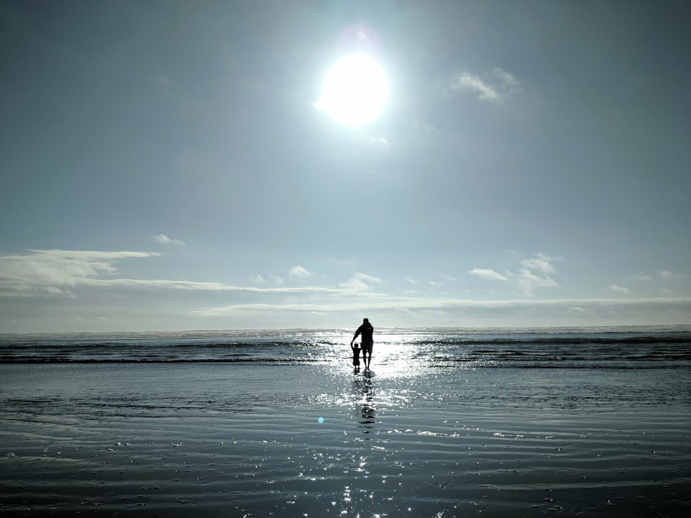 homme et enfant en bas âge marchant sur le bord de la mer