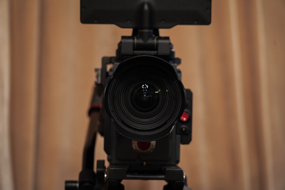appareil photo reflex numérique noir à côté d’un rideau marron