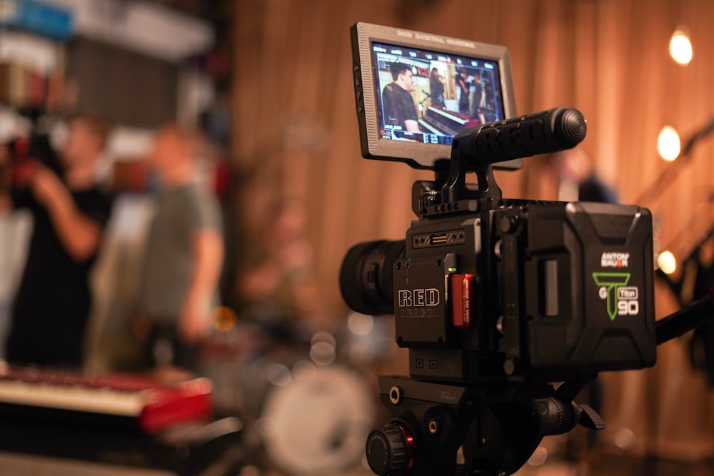 selective focus photography of video camera pointing towards people playing instruments inside room