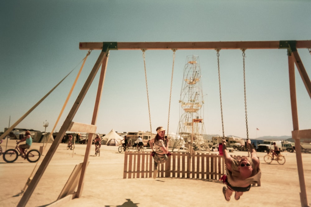 two persons riding swing during day