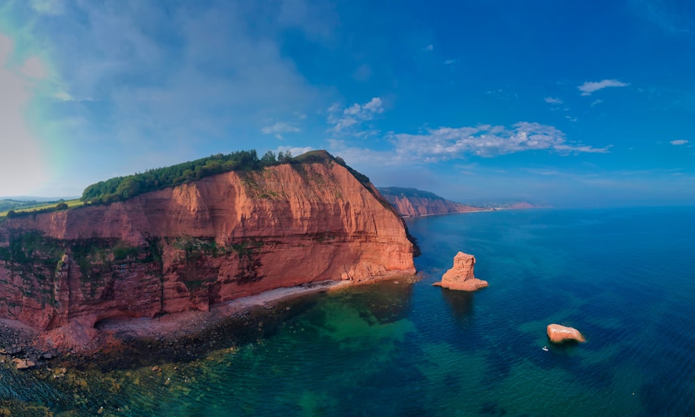 brown rock formation by the body of water at daytime