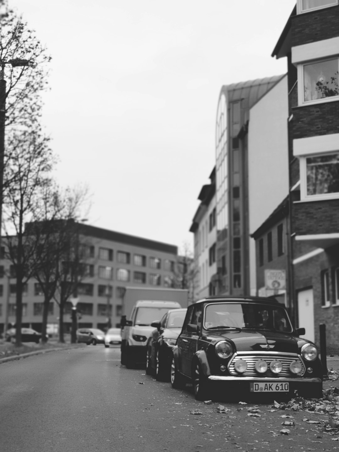 grayscale photo of vehicles parked near buildings