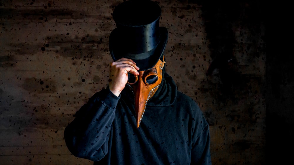 man wearing long-nosed mask and black hat