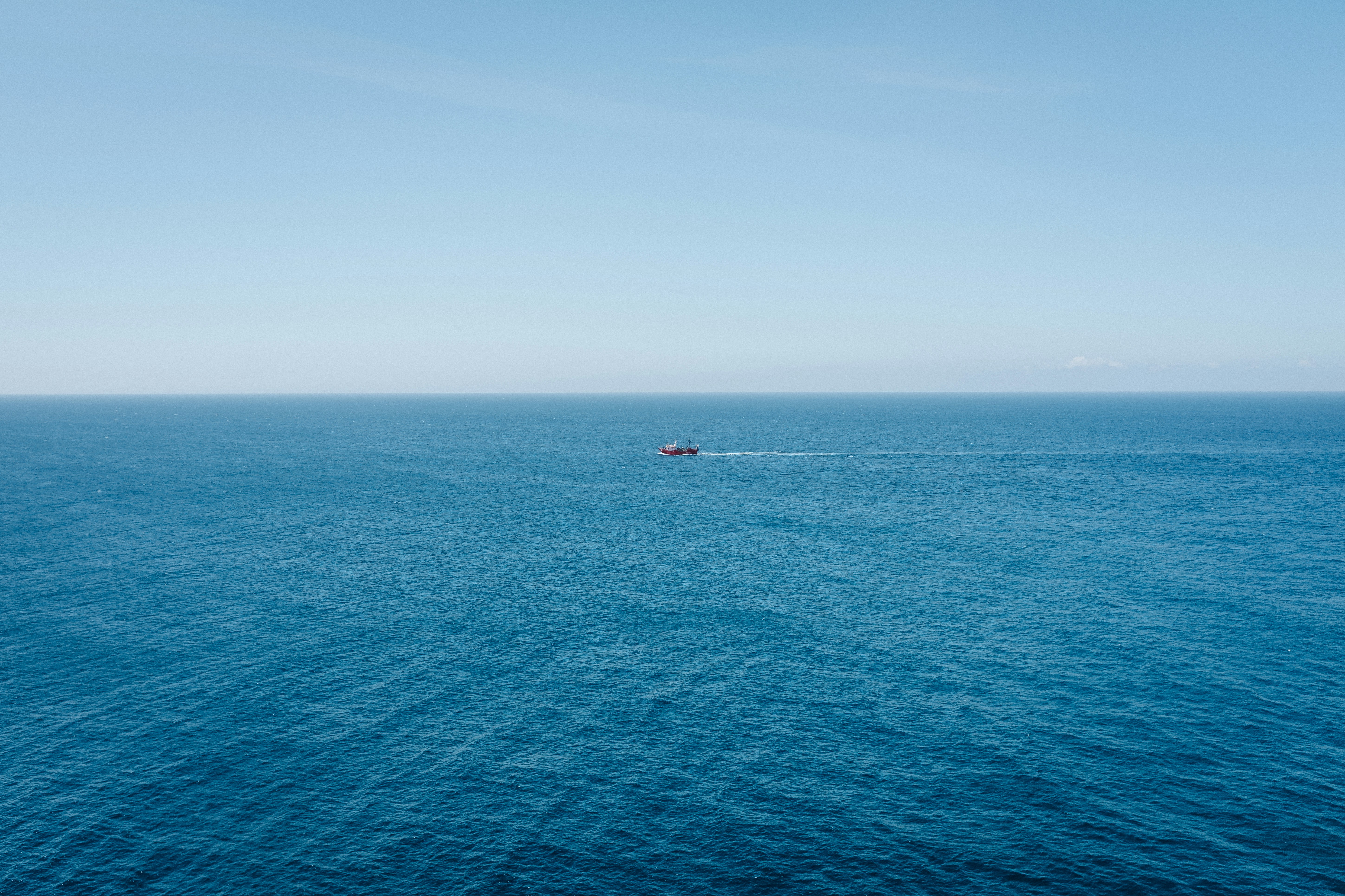 massive autonomous container ship navigating calm deep blue ocean waters under a clear sky
