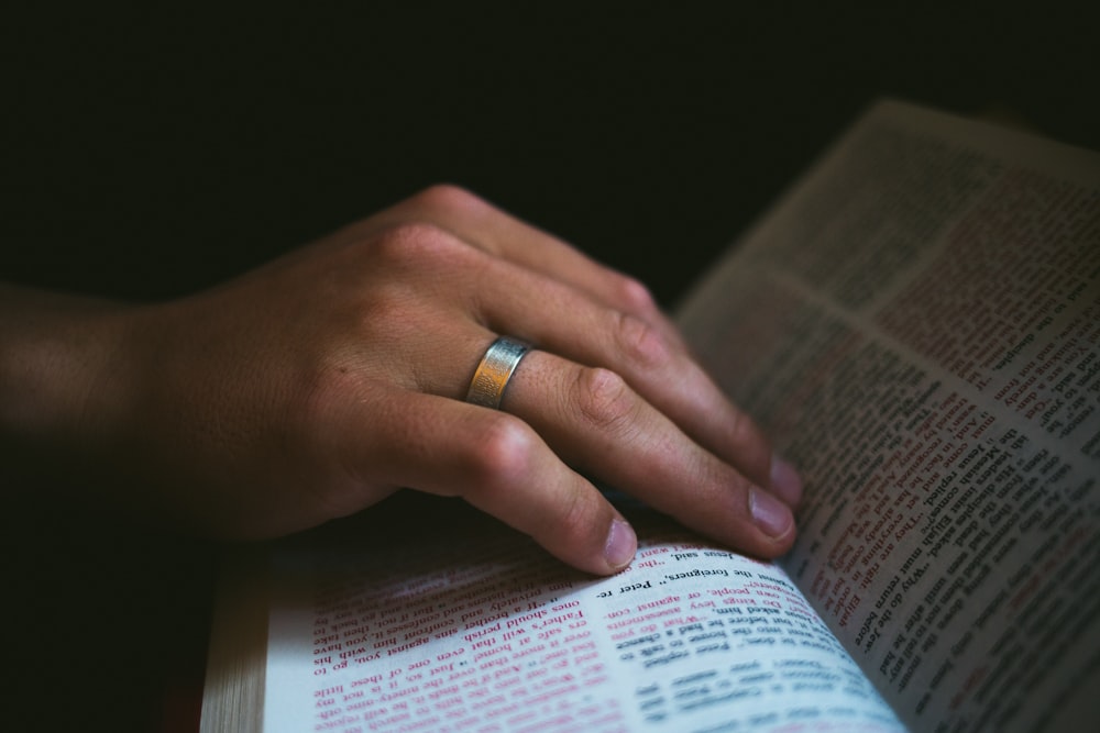 eine Person mit einem Ring am Finger, die ein Buch liest