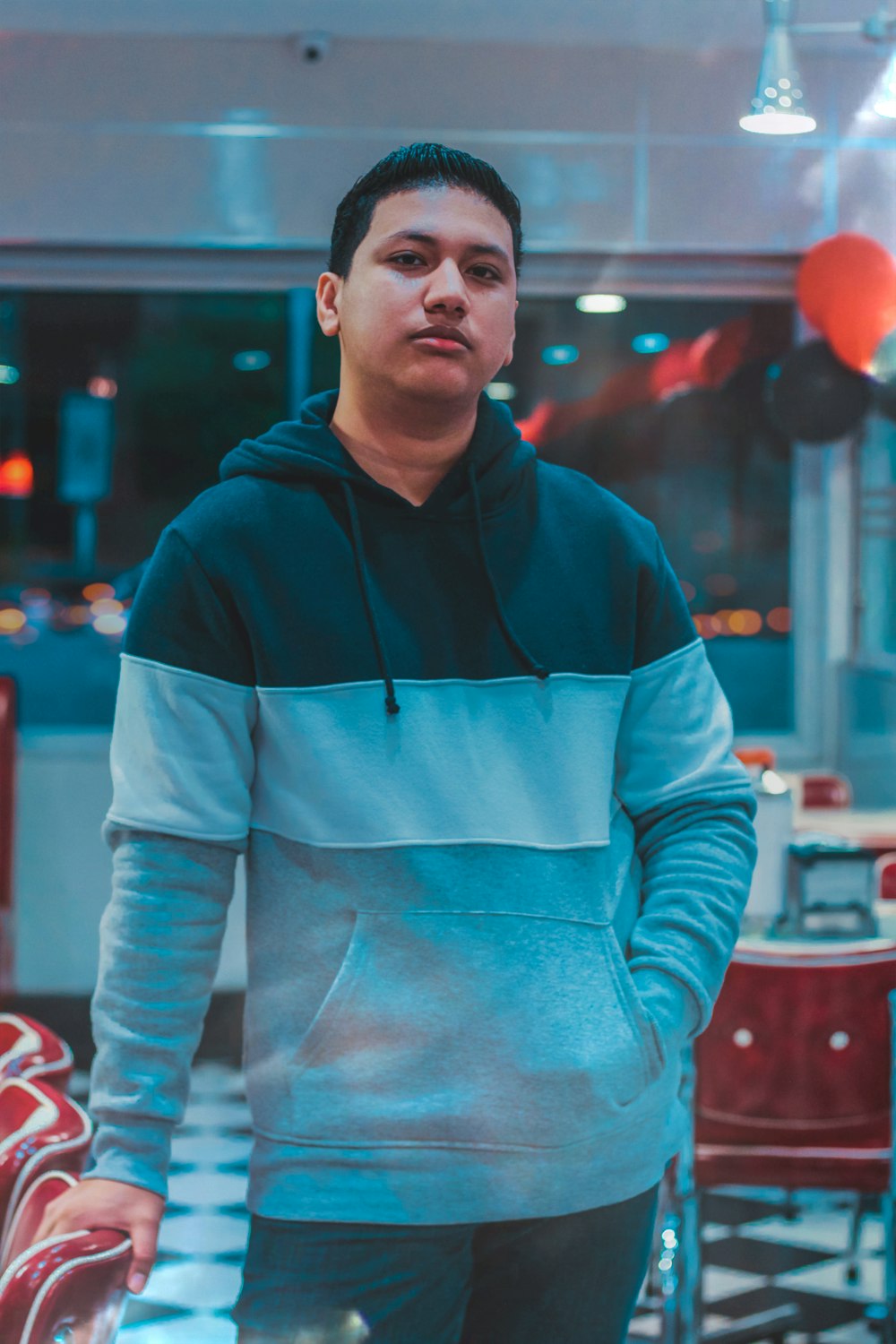 man wearing black, white, and gray hoodie holding red chair