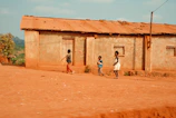 Children playing near a traditional mud hut with thatched roof.