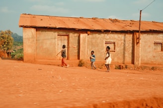three kids standing beside concrete building