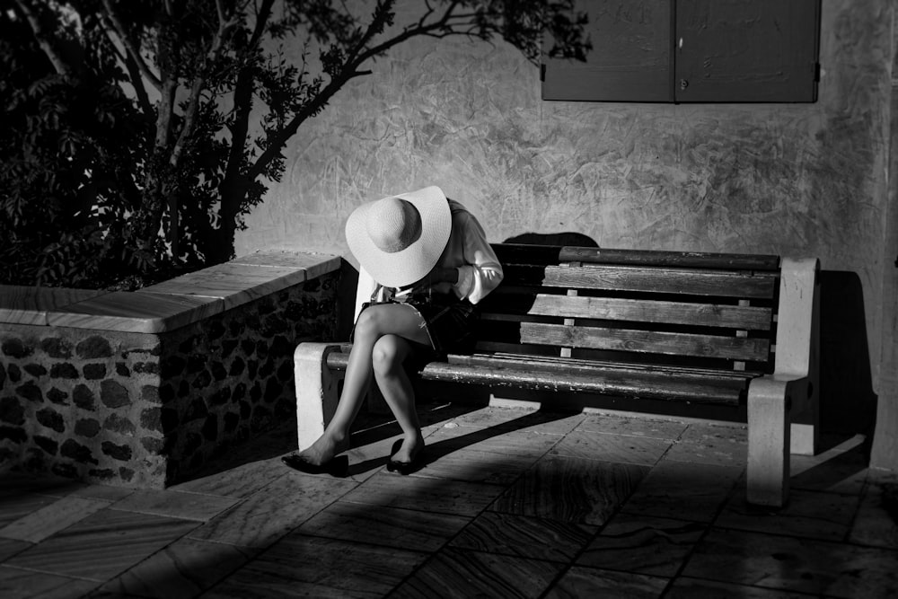 grayscale photo of woman sitting onbench
