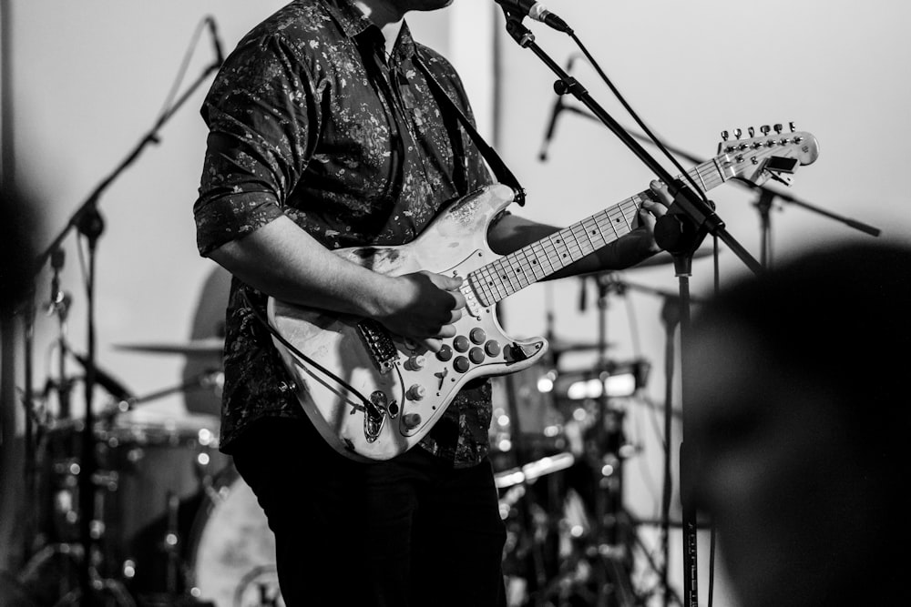 man playing guitar grayscale photo